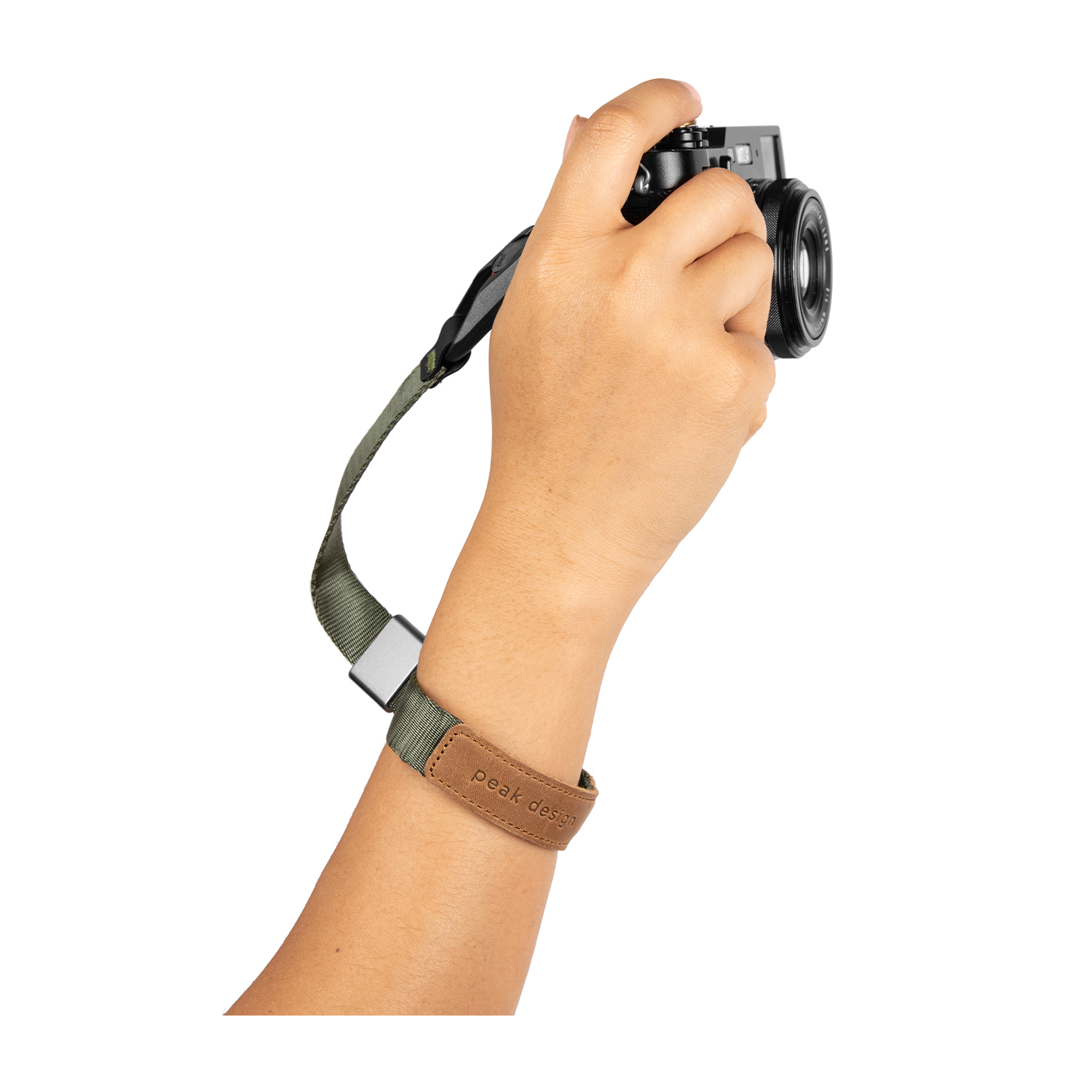 La mano di una persona che tiene una fotocamera con un cinturino da polso marrone e verde.