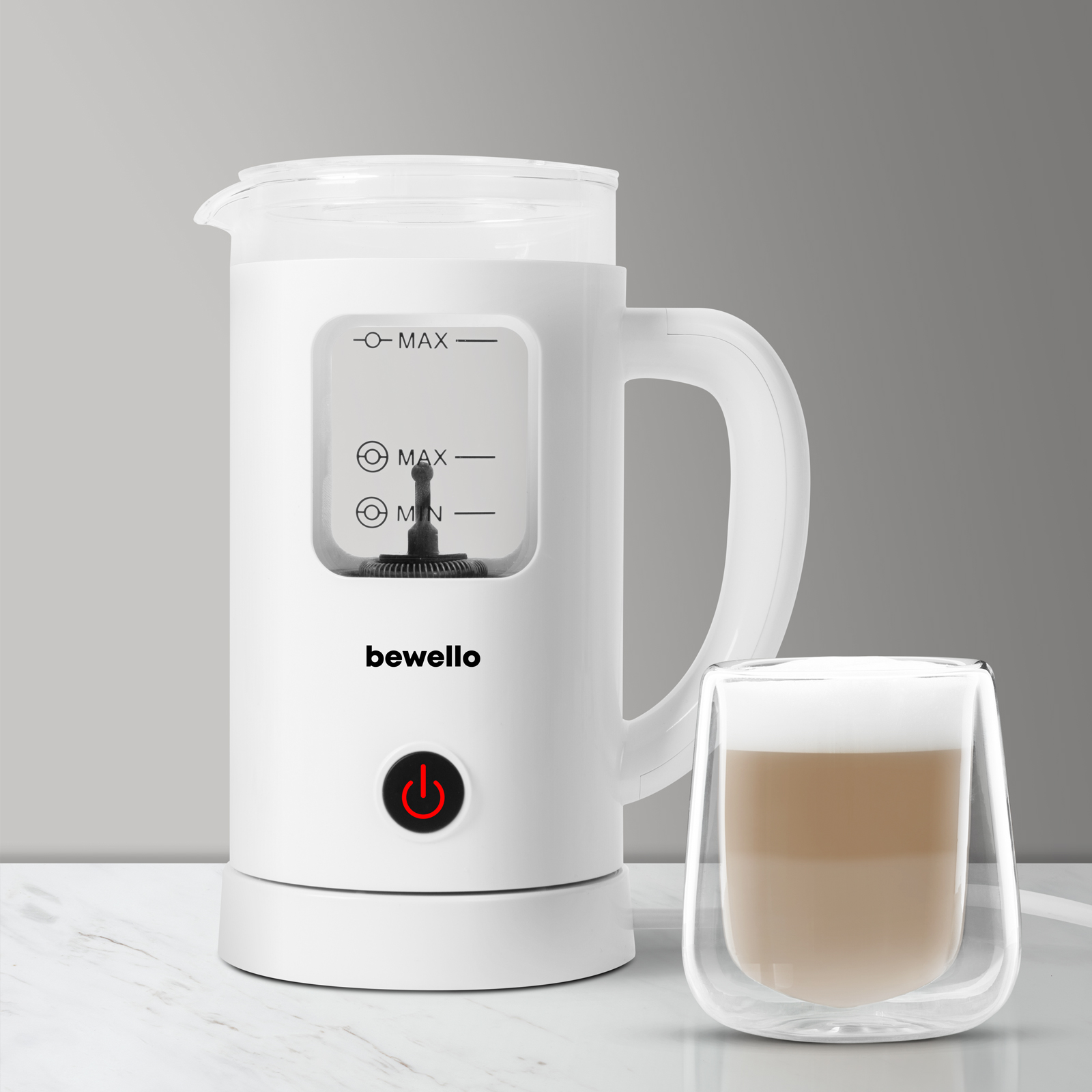 Fehér tejhabosító egy pohár latte-val. A habosítón van egy bekapcsológomb és egy fogantyú.