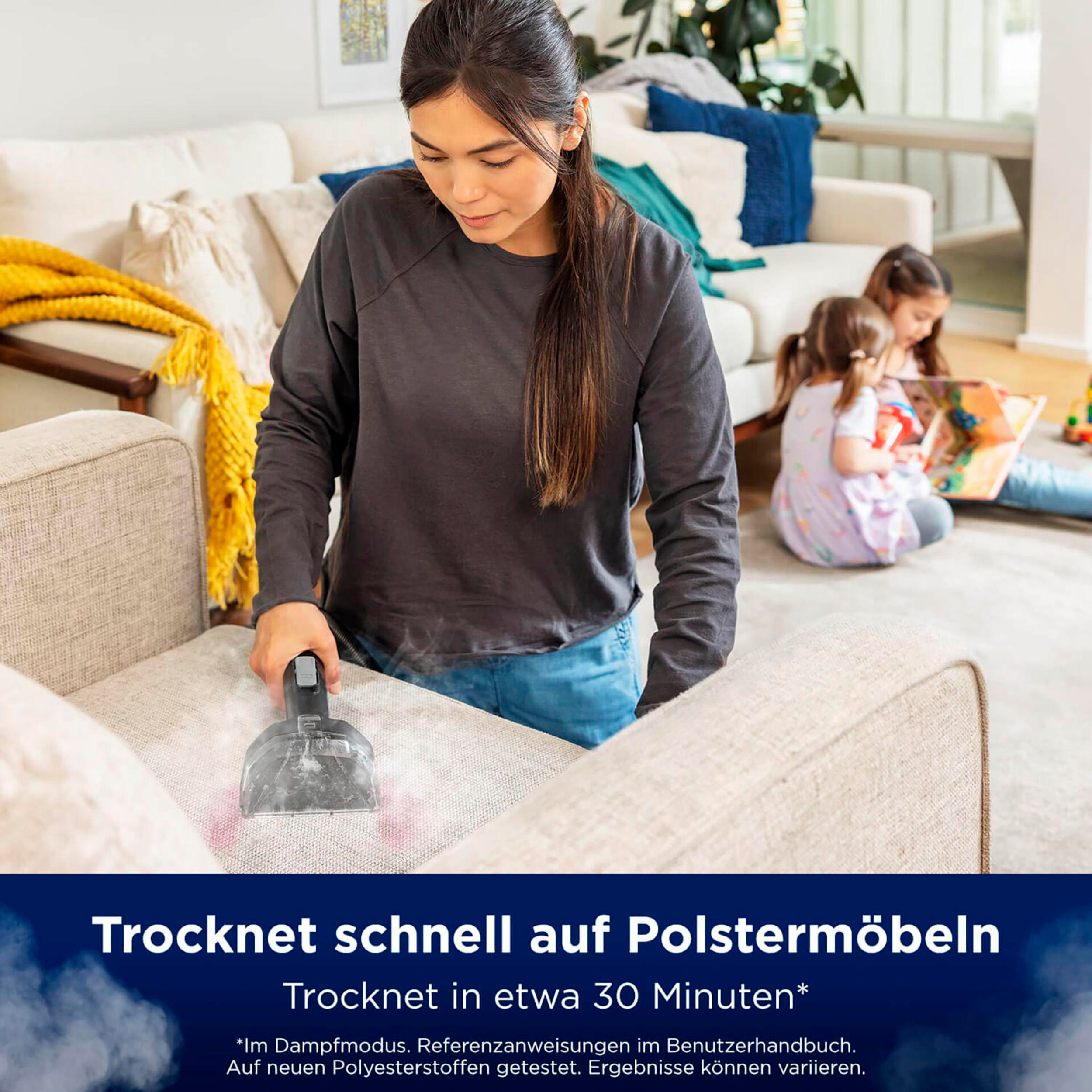 Frau benutzt Staubsauger auf Sofa. Text: Trocknet schnell auf Polstermöbeln - trocknet schnell auf Polstern.