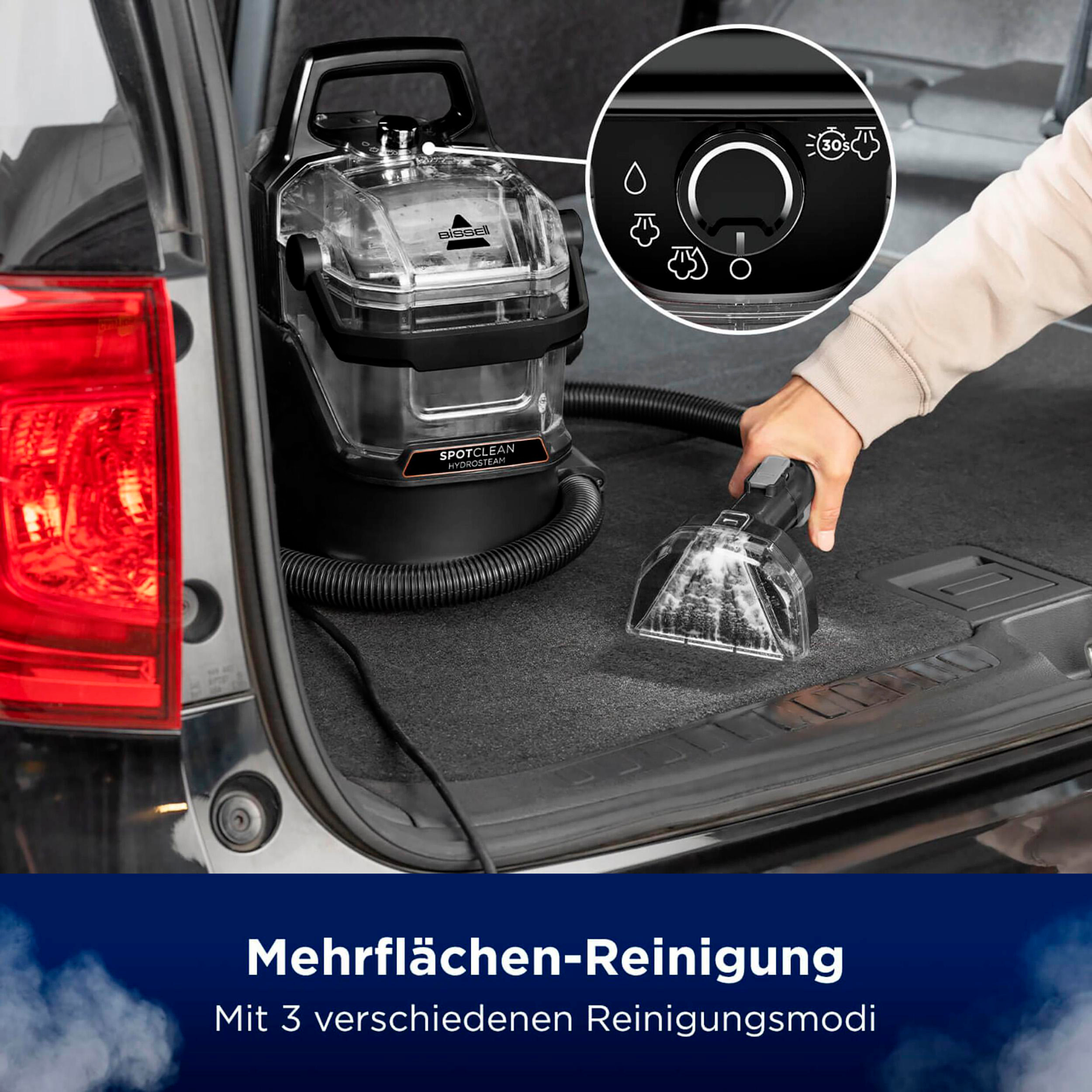 Ein schwarzer und klarer Bissell SpotClean ProHeat Dampfreiniger befindet sich in einem Kofferraum. Text: Mehrflächen-Reinigung.