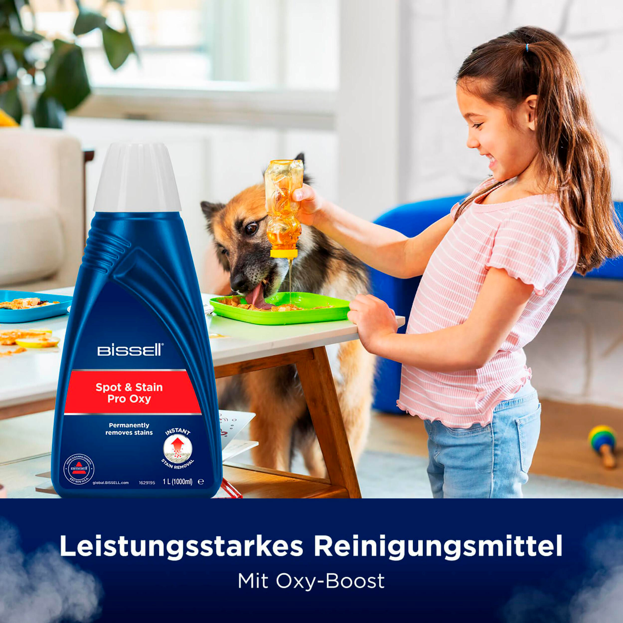 Ein Mädchen und ein Hund interagieren mit einer Fleckenentfernerflasche und einer grünen Ablage. Produktetikett sichtbar.