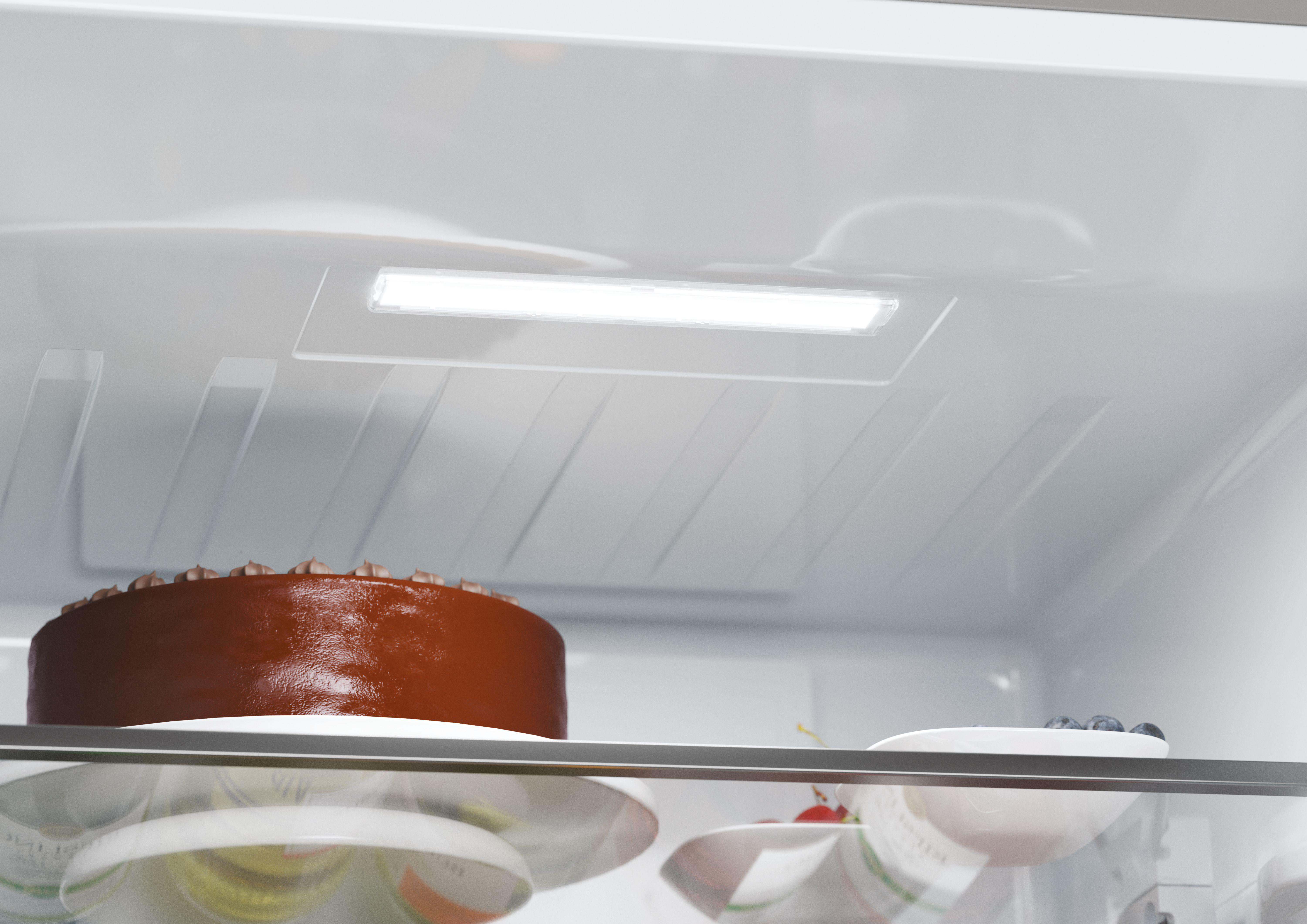 Innere eines Kühlschranks mit einem Kuchen und Tellern.