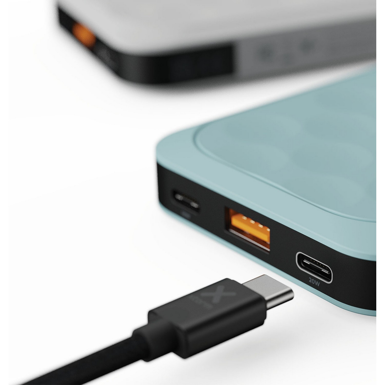 Gros plan sur une batterie externe bleue avec un câble branché et une autre floue.