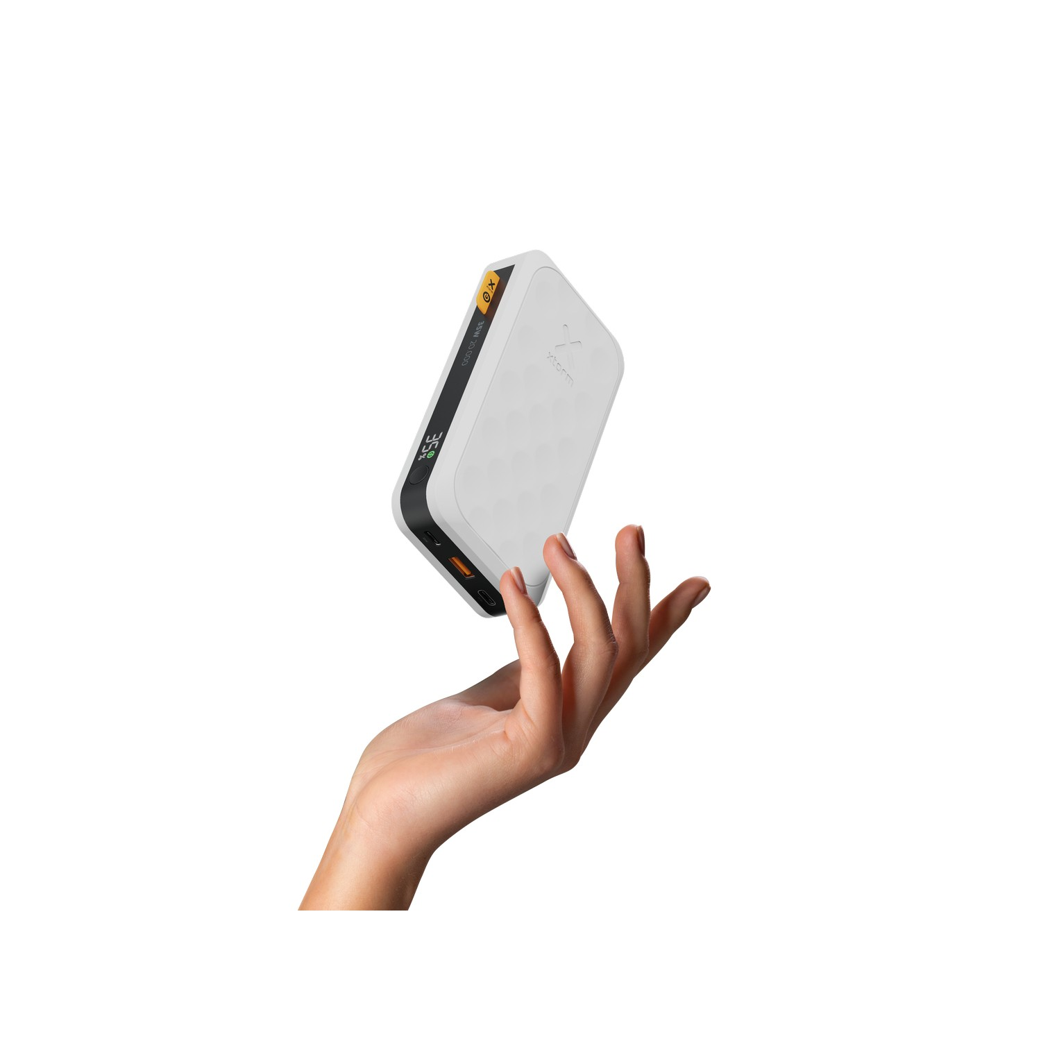 Une main tenant une batterie externe blanche et noire. La batterie flotte dans les airs.