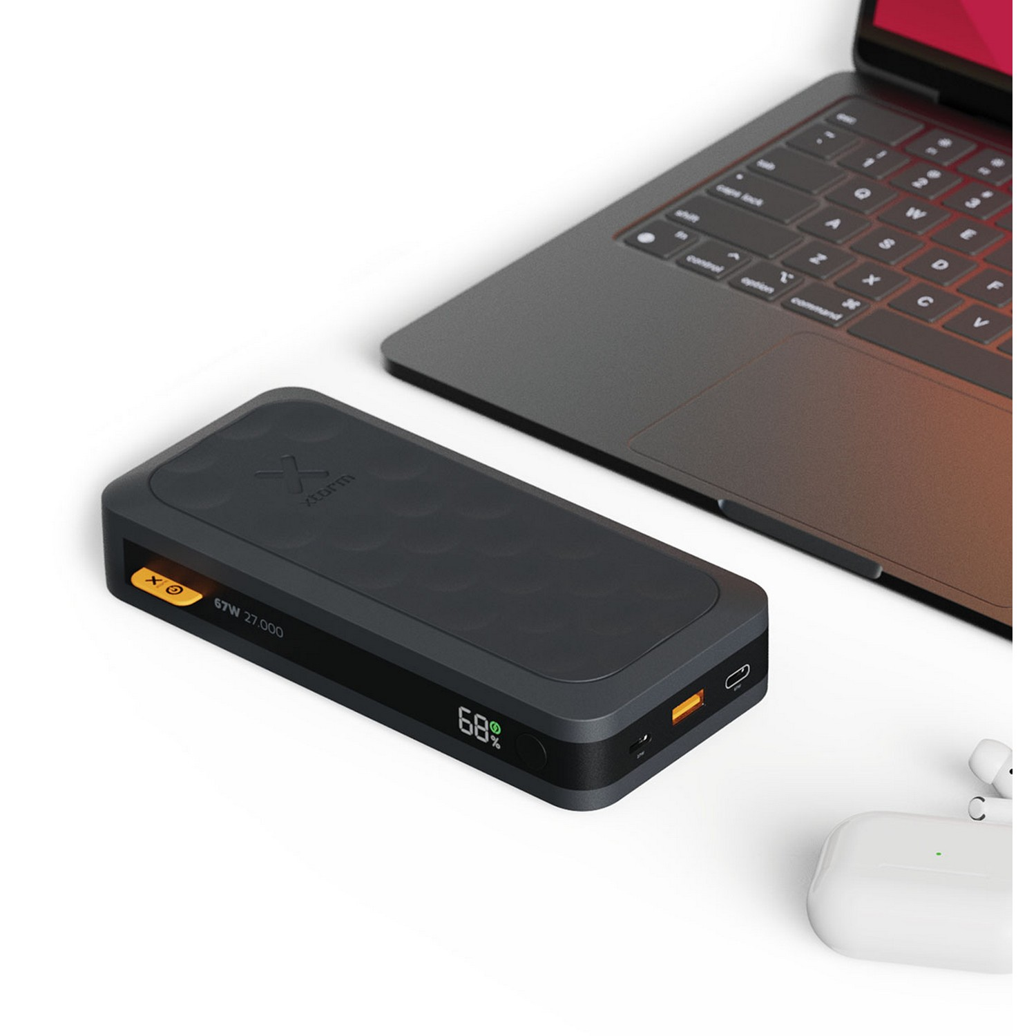 Batterie externe noire, ordinateur portable et AirPods. Affiche 68% et 67W.