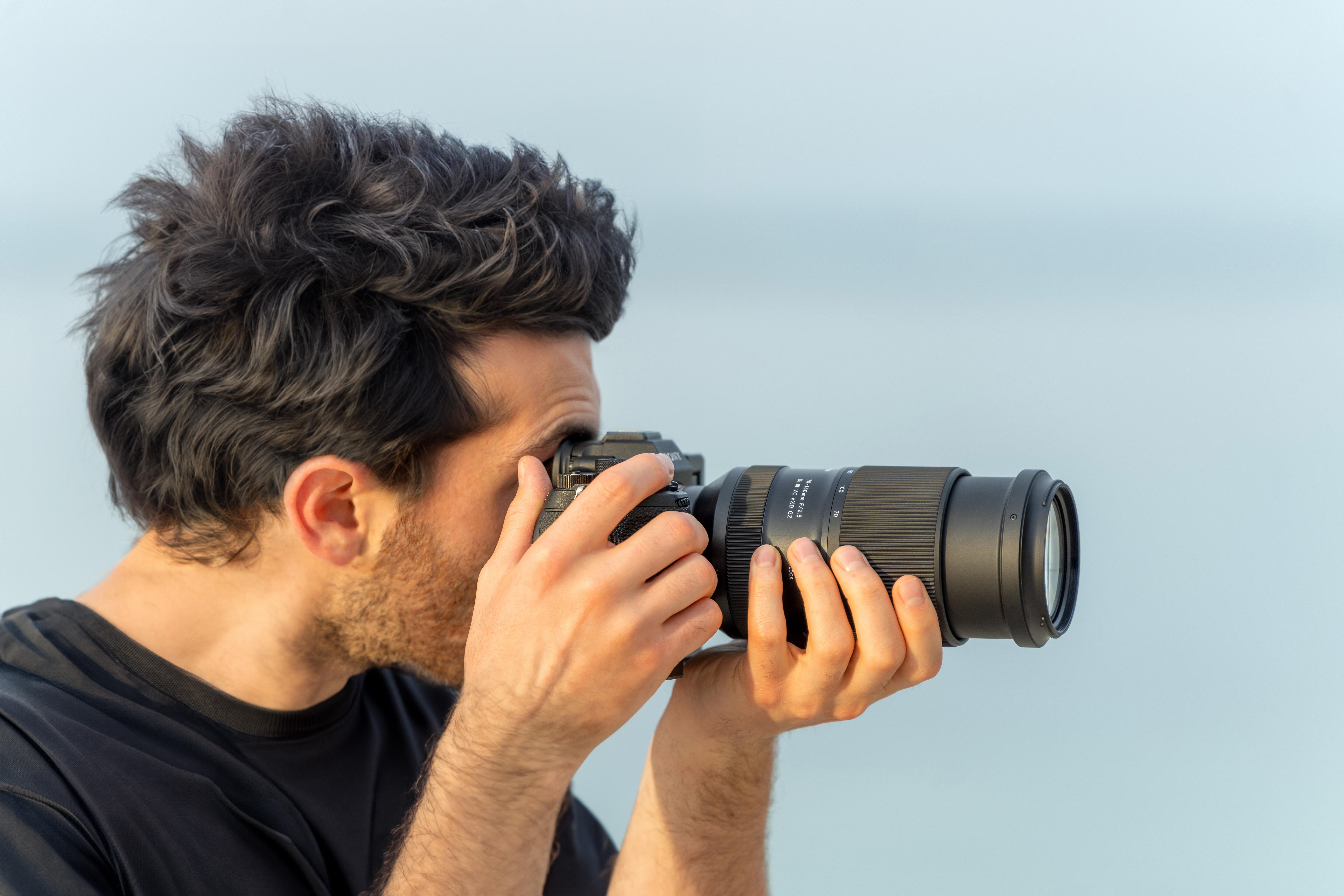 Mann macht Fotos mit einer Kamera. Blauer Himmel im Hintergrund.