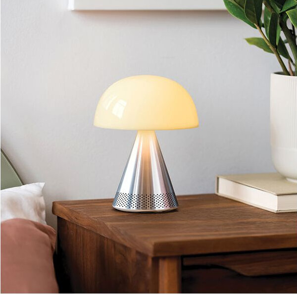 Lampa w kształcie grzyba ze srebrną podstawą, stojąca na drewnianym stole.