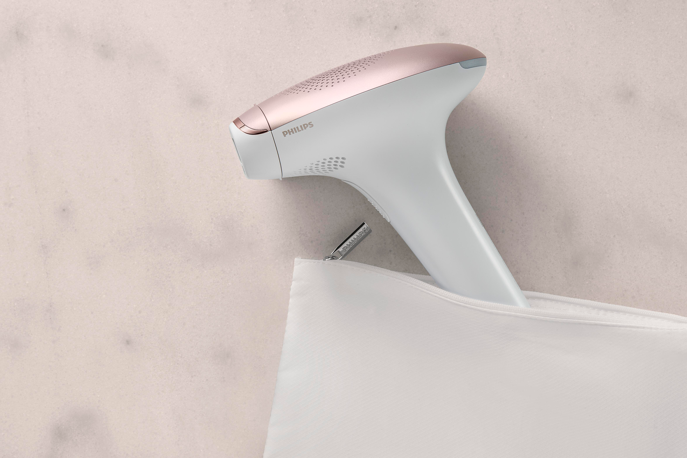Wit en roségoud Philips ontharingsapparaat, uit een witte pouch.