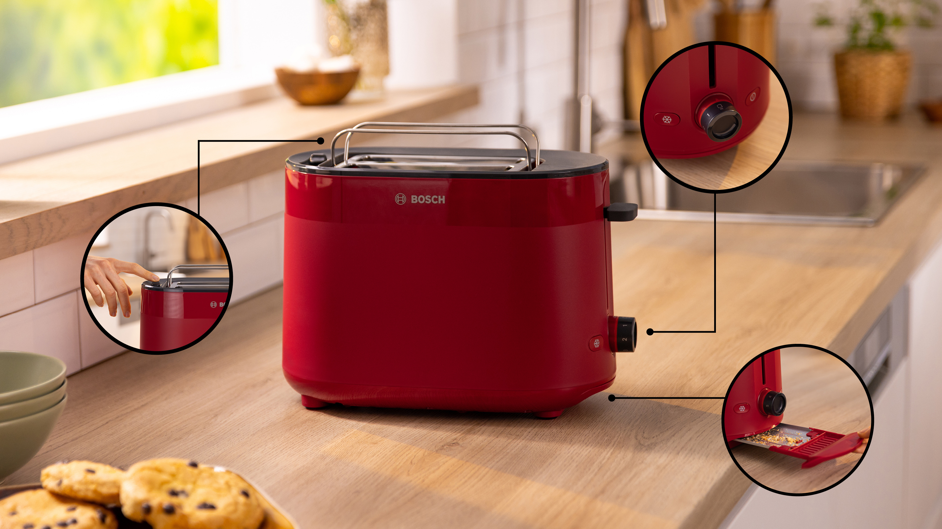 Roter Toaster auf einer Holztheke mit Nahaufnahmedetails. Ein Teller mit Keksen im Vordergrund.