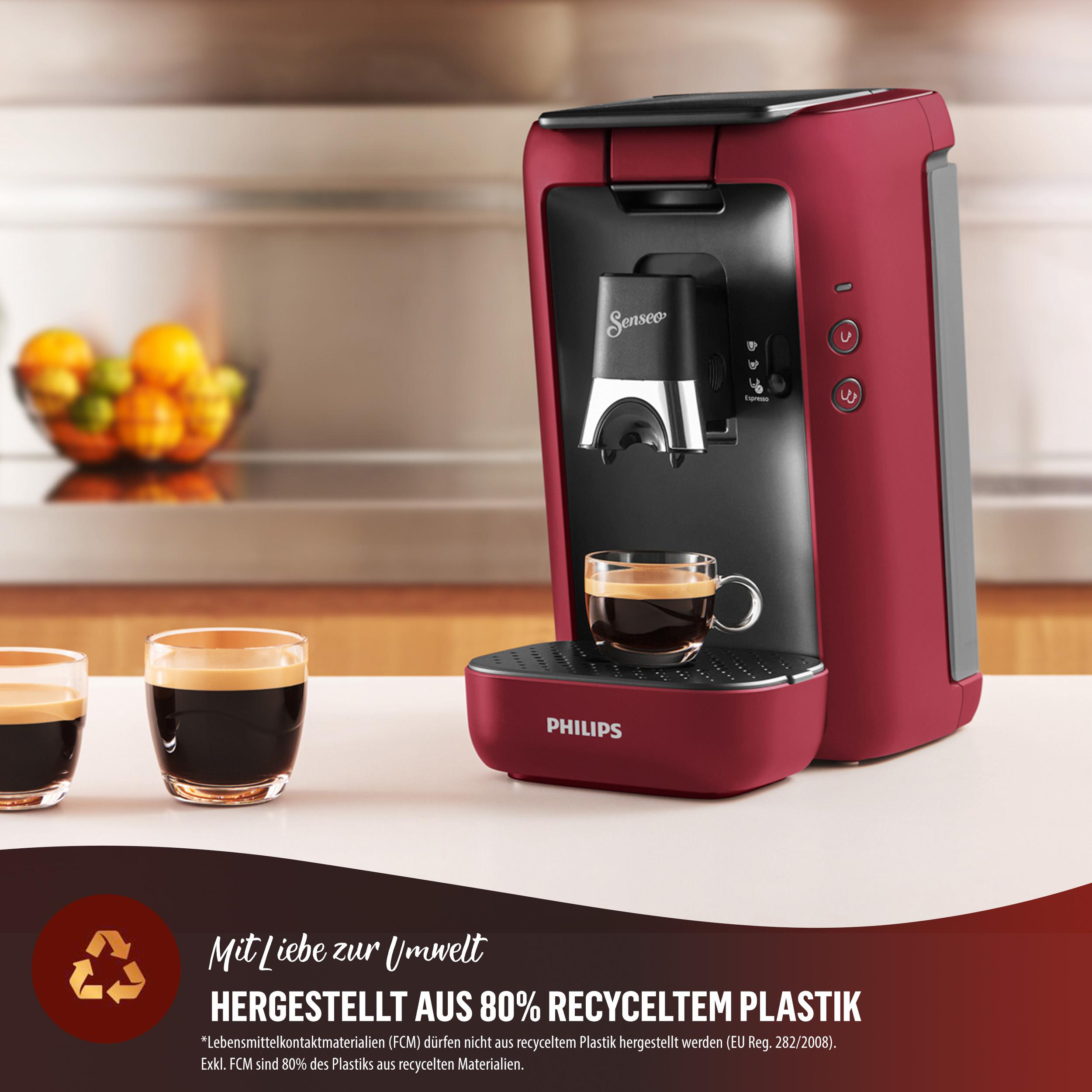 Eine rote Kaffeemaschine mit einer Tasse Kaffee und zwei weiteren Tassen Kaffee auf einem weißen Tisch.