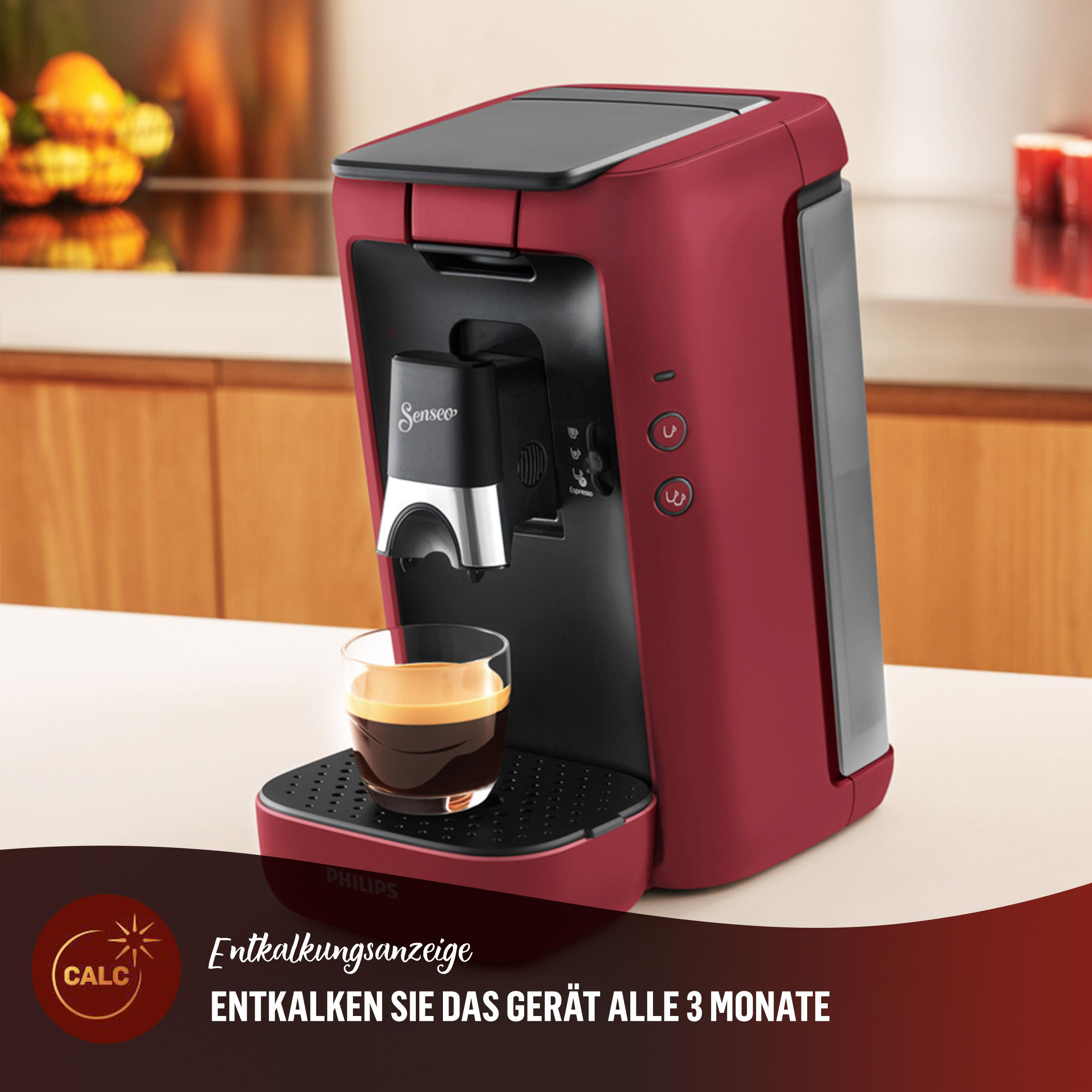 Rote Kaffeemaschine mit Glas. Kaffee wird gegossen. Braune und weiße Oberfläche.