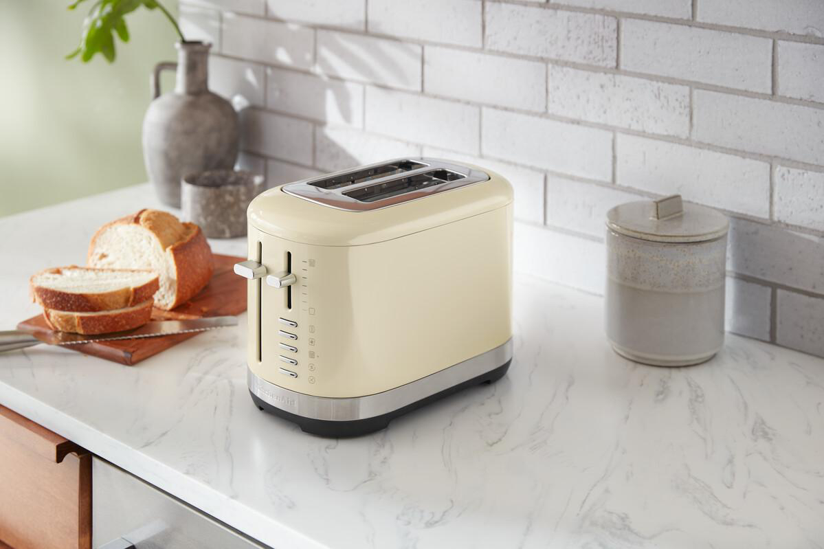 Ein cremefarbener Toaster mit zwei Schlitzen und eine Auswahl an Toastbrotscheiben.