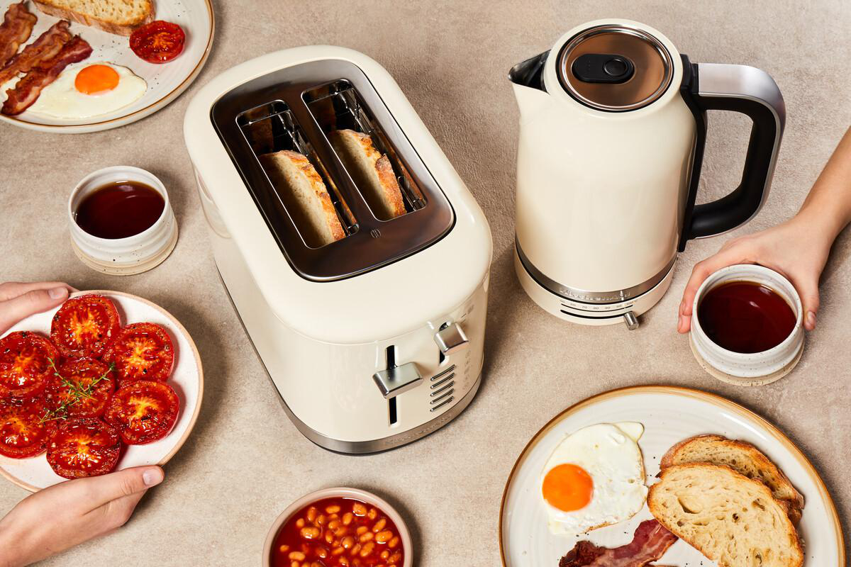 Frühstücksangebot mit Toaster, Wasserkocher, Eiern, Speck und Tomaten.