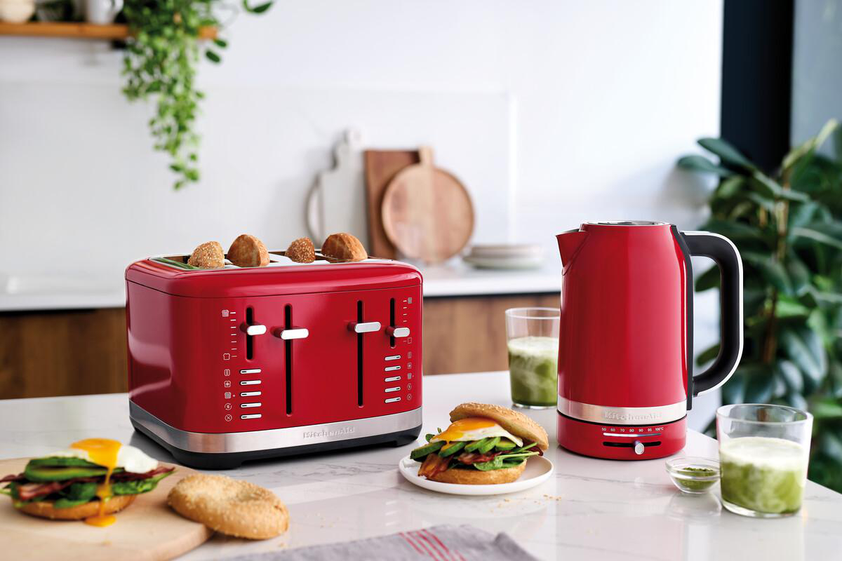 Roter Toaster und Wasserkocher auf einer Theke mit einem Sandwich und einem Getränk.