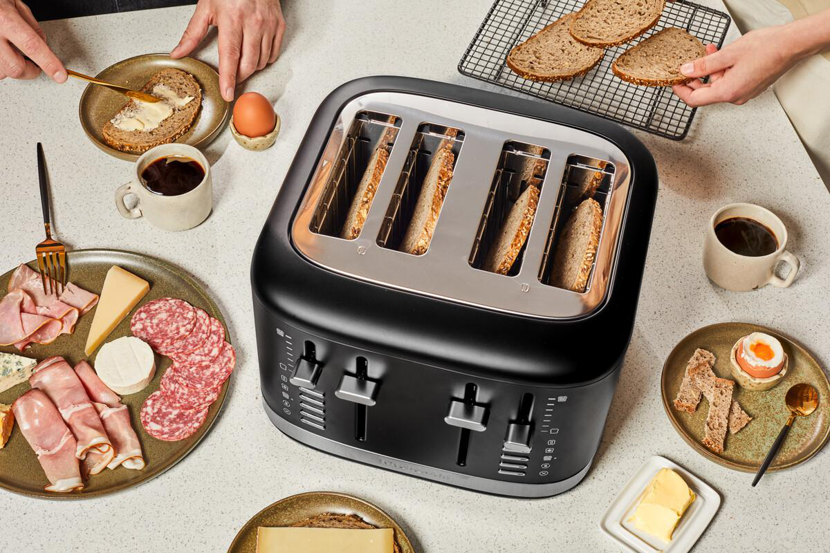Getoastetes Brot, Kaffee und Essen auf einem Tisch mit einem schwarzen Toaster.