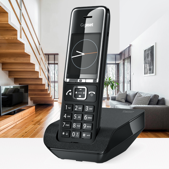 Fekete vezeték nélküli telefon a fekete alapon. Lépcső és kanapé a háttérben.