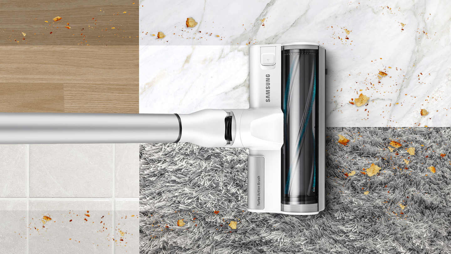 Un aspirateur Samsung sur diverses surfaces avec des miettes. Les surfaces incluent le bois, le marbre, les carreaux et la moquette.