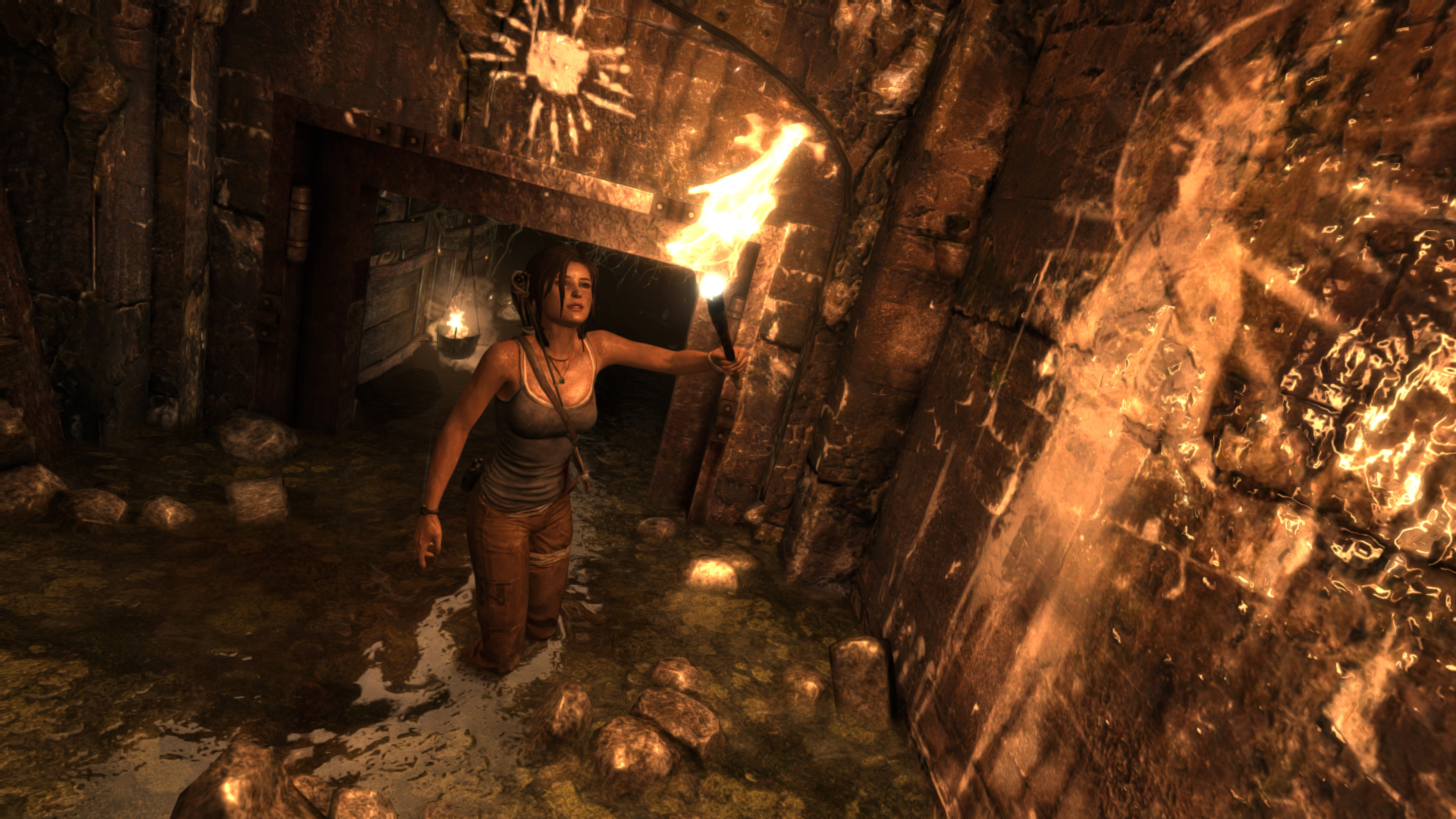 Frau in einer Höhle mit einer Fackel, Wasser am Boden und Steinwände.