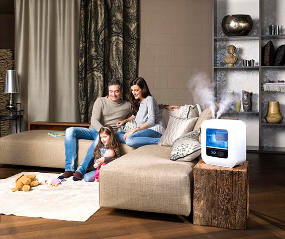 Familie auf einem Sofa mit Luftbefeuchter, Lampe und Dekorationsartikeln.