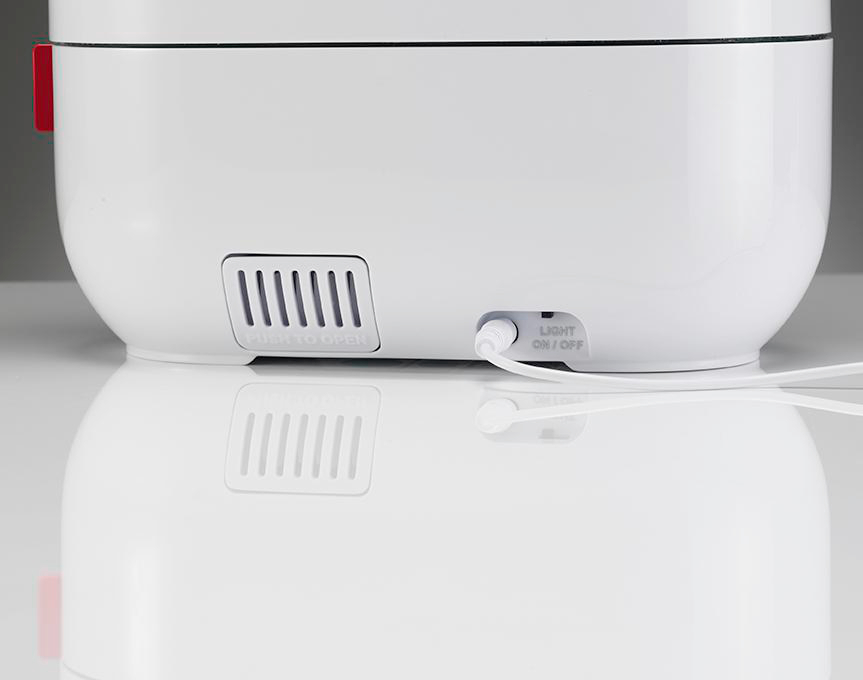 Nahaufnahme eines weißen Geräts mit einem Lüftungsschlitz und einem eingesteckten Netzkabel.