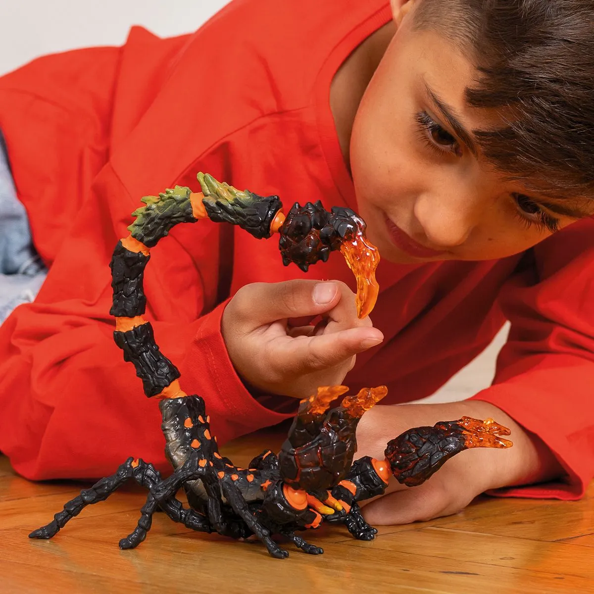 Junge betrachtet ein Skorpion-Spielzeug; Skorpion ist schwarz und orange mit detaillierten Segmenten.
