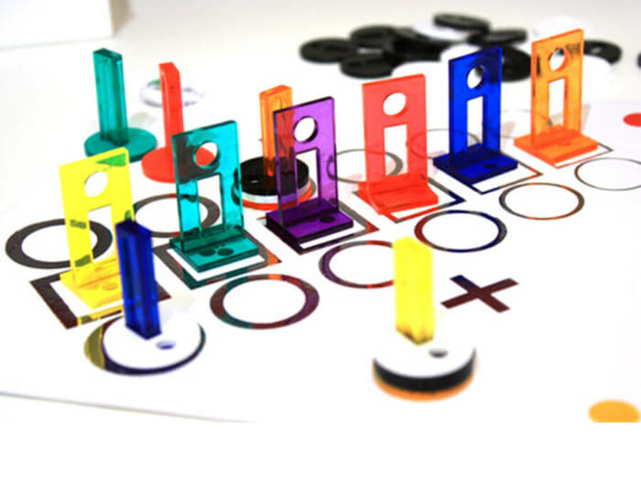 Több színes tic-tac-toe darab egy fehér táblán, rácsozattal.