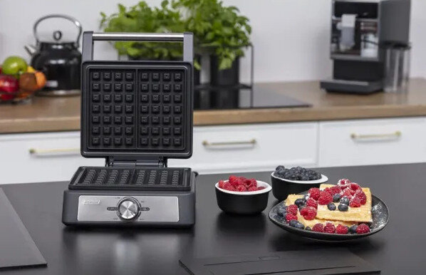 Gofrownica z goframi, malinami i borówkami. Kuchnia z czajnikiem i ekspresem do kawy.