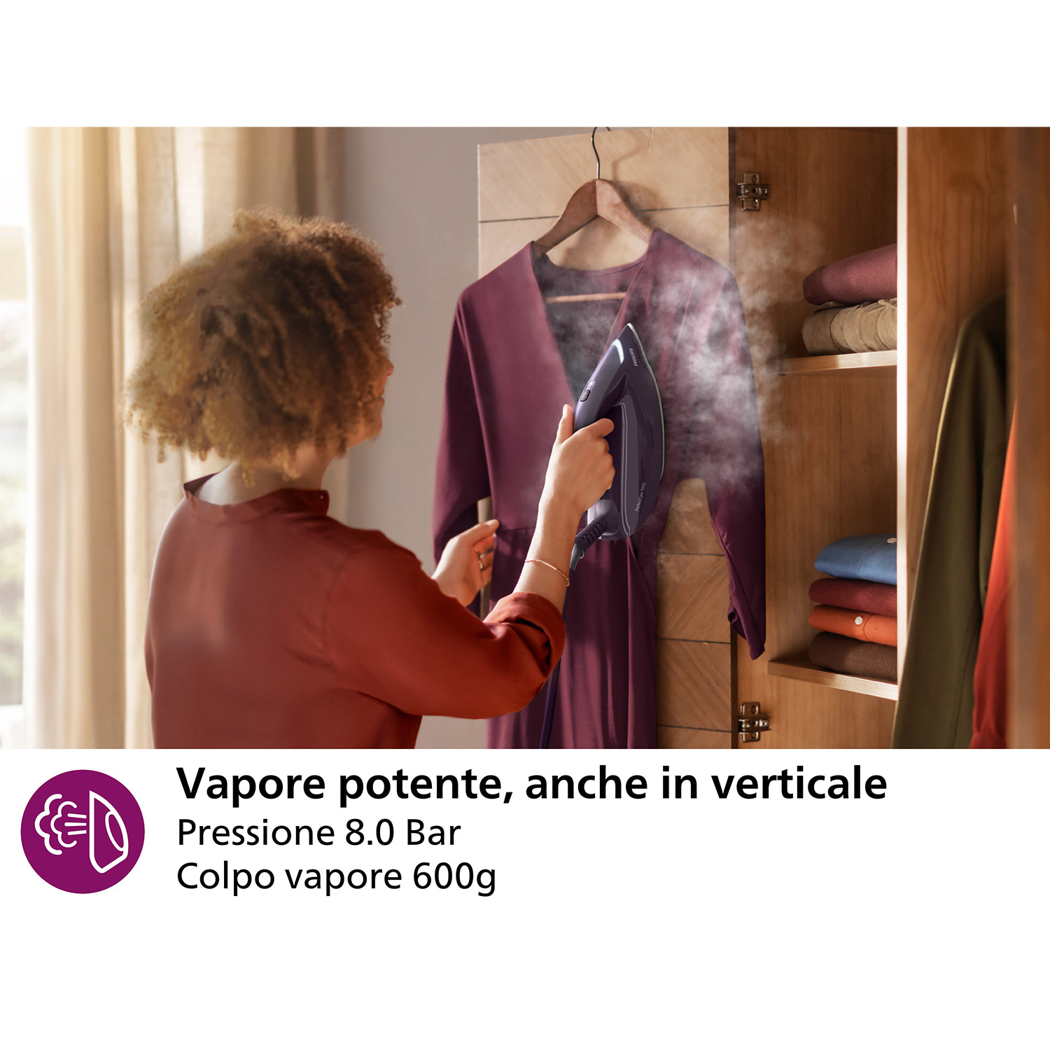 Una donna che stira un vestito a vapore. Il testo recita: Vapore potente, anche in verticale, pressione di 8,0 bar.