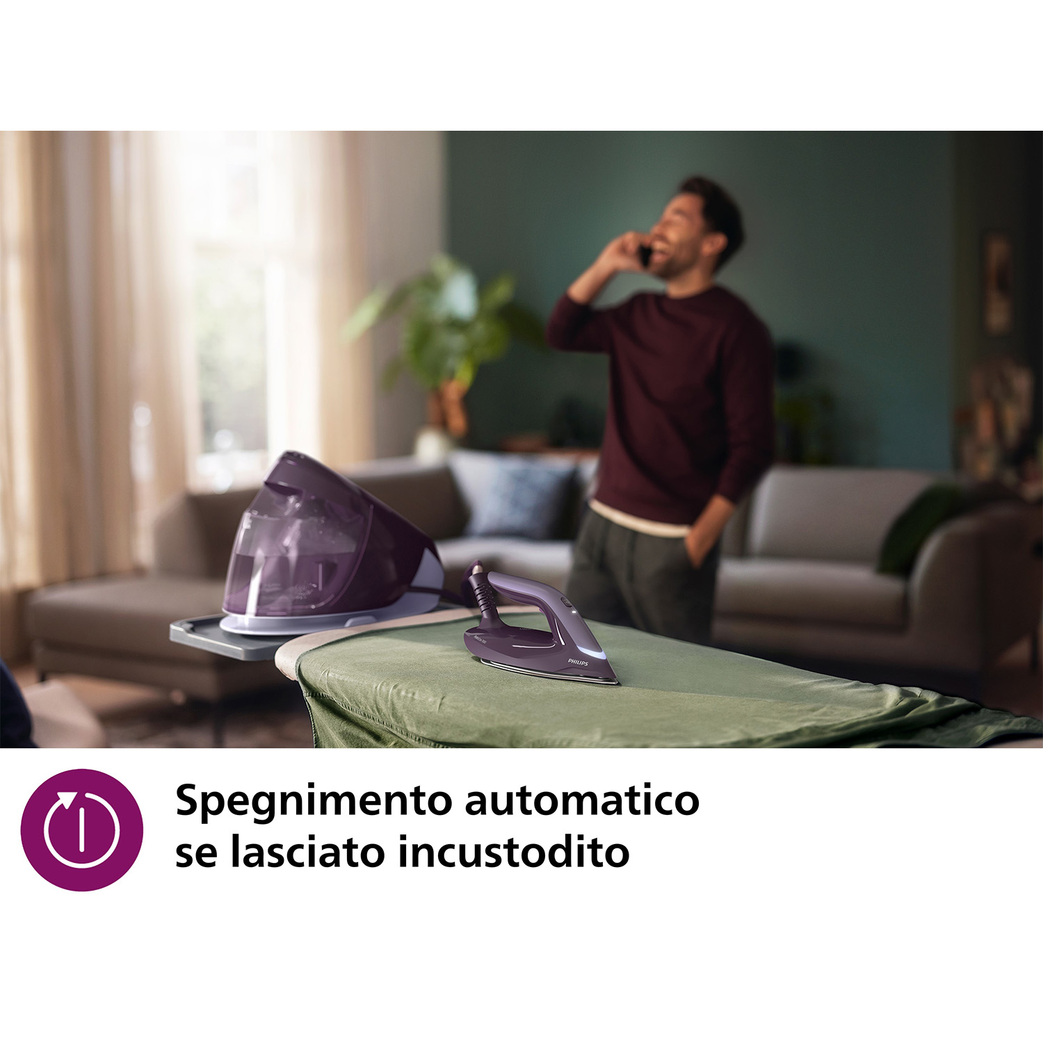 Un ferro da stiro e un generatore di vapore viola su un'asse da stiro. Uomo che parla al telefono.