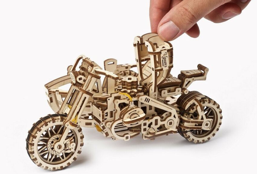 Fa motorkerékpár modell egy kézben. A modell barna, bonyolult részletekkel.