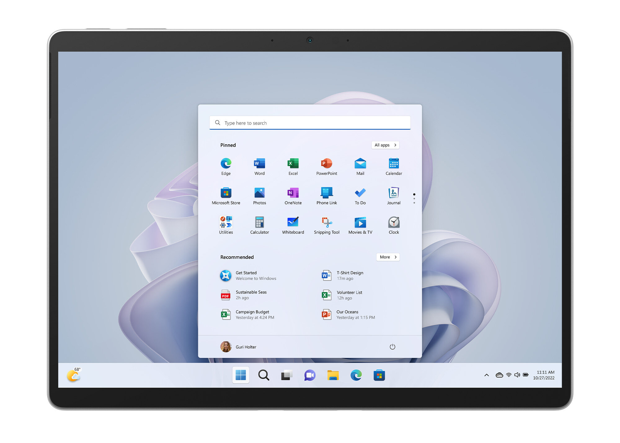Tablet z ekranem startowym Windows, pokazujący ikony aplikacji i pasek wyszukiwania, na białej powierzchni, czarna ramka.