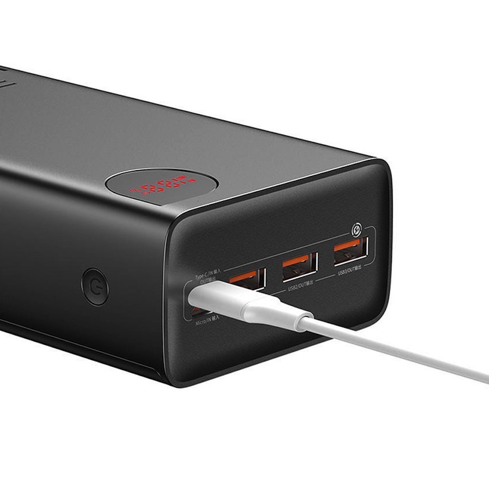 Kırmızı rakamların göründüğü ekranlı, siyah powerbank, çoklu USB portları ve beyaz şarj kablosu.