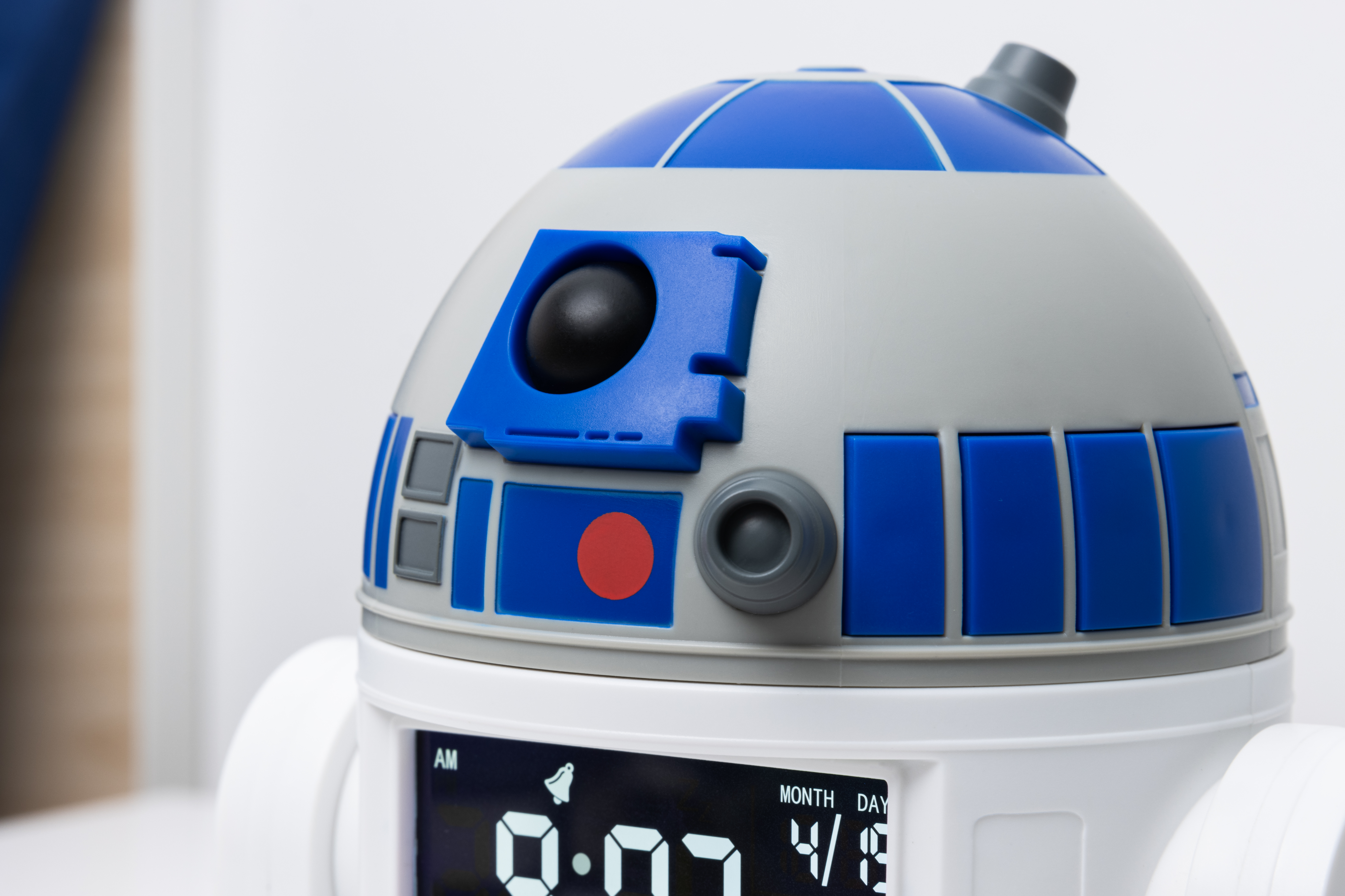 R2-D2 Wecker. Weißer und blauer Roboterkopf. Digitalanzeige mit Uhrzeit und Datum.