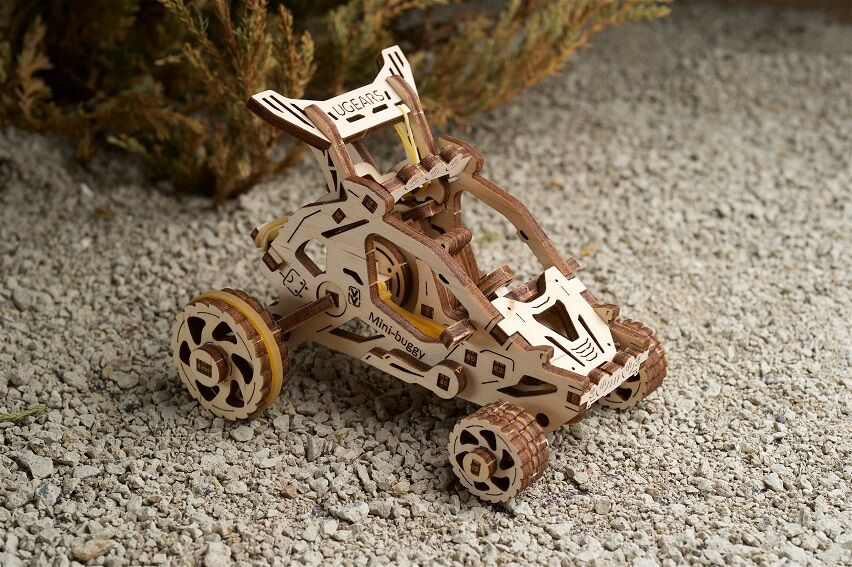 Fa mini-buggy modell, kőfelületen, fa kerekekkel és sárga kerettel.