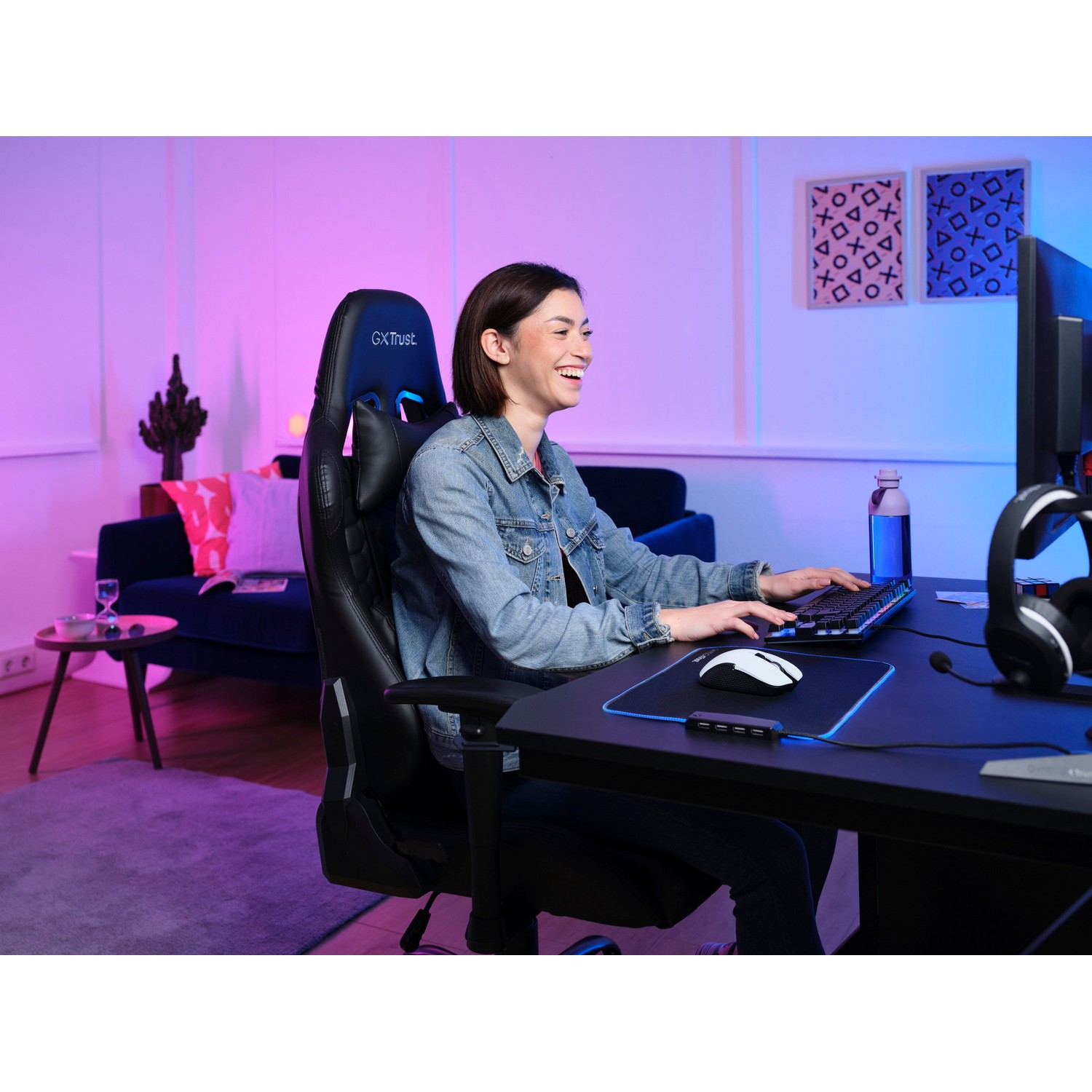 Woman gaming with keyboard and mouse. Pink and blue lights illuminate the gaming setup.