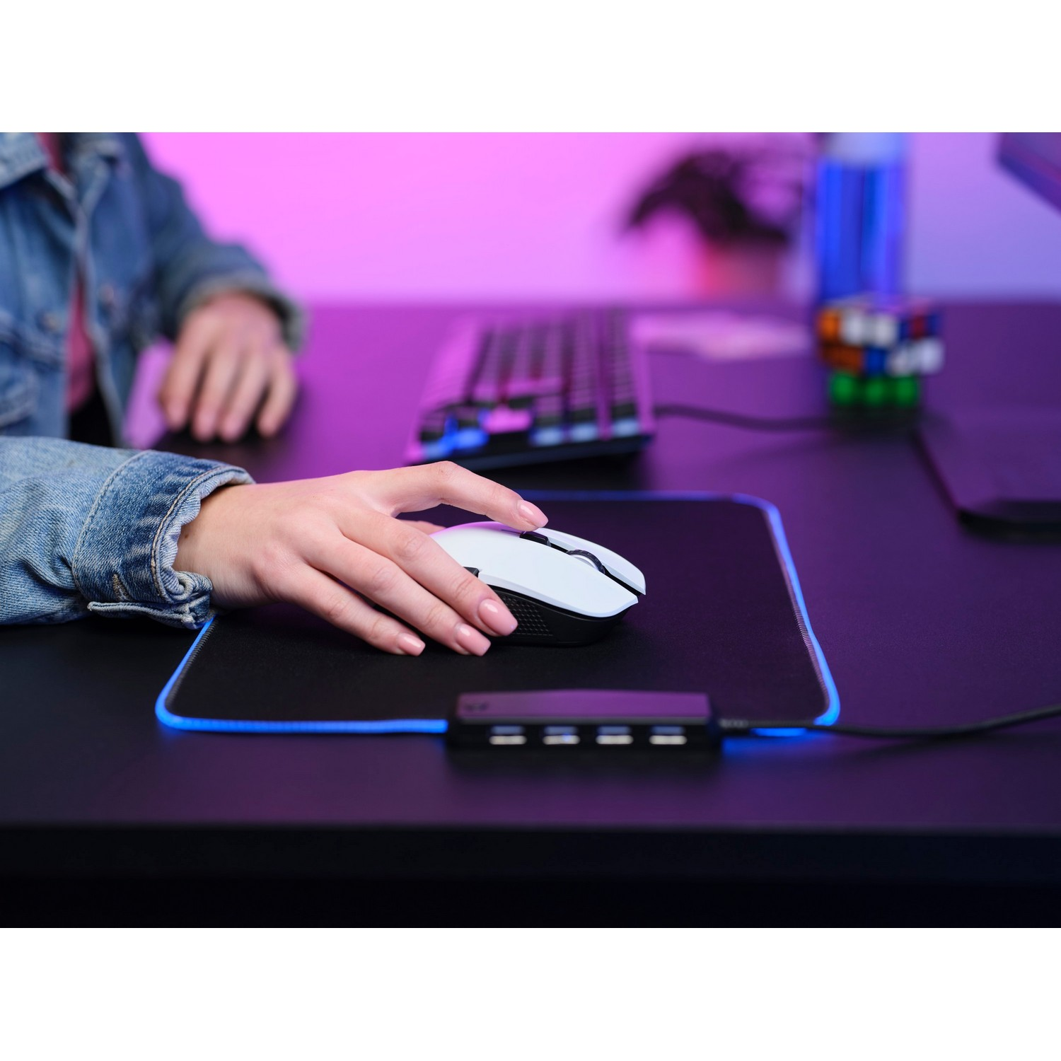 Person using a white mouse on a black mousepad with blue led lights, gaming setup.