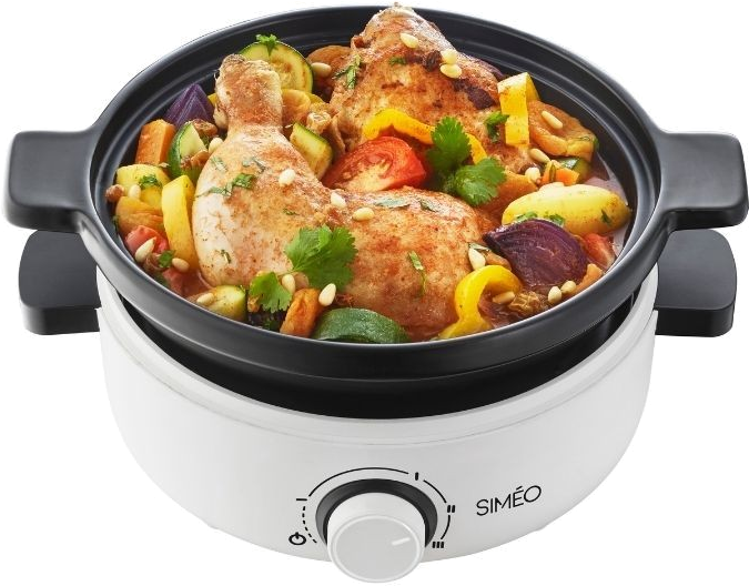 A white and black cooking appliance with chicken and vegetables inside, close up.