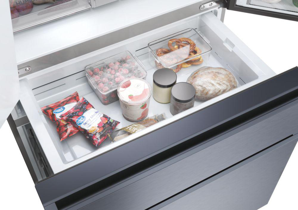 Geöffnete Kühlschublade mit gefrorenen Beeren, Brot und anderen verpackten und unverpackten Lebensmitteln.