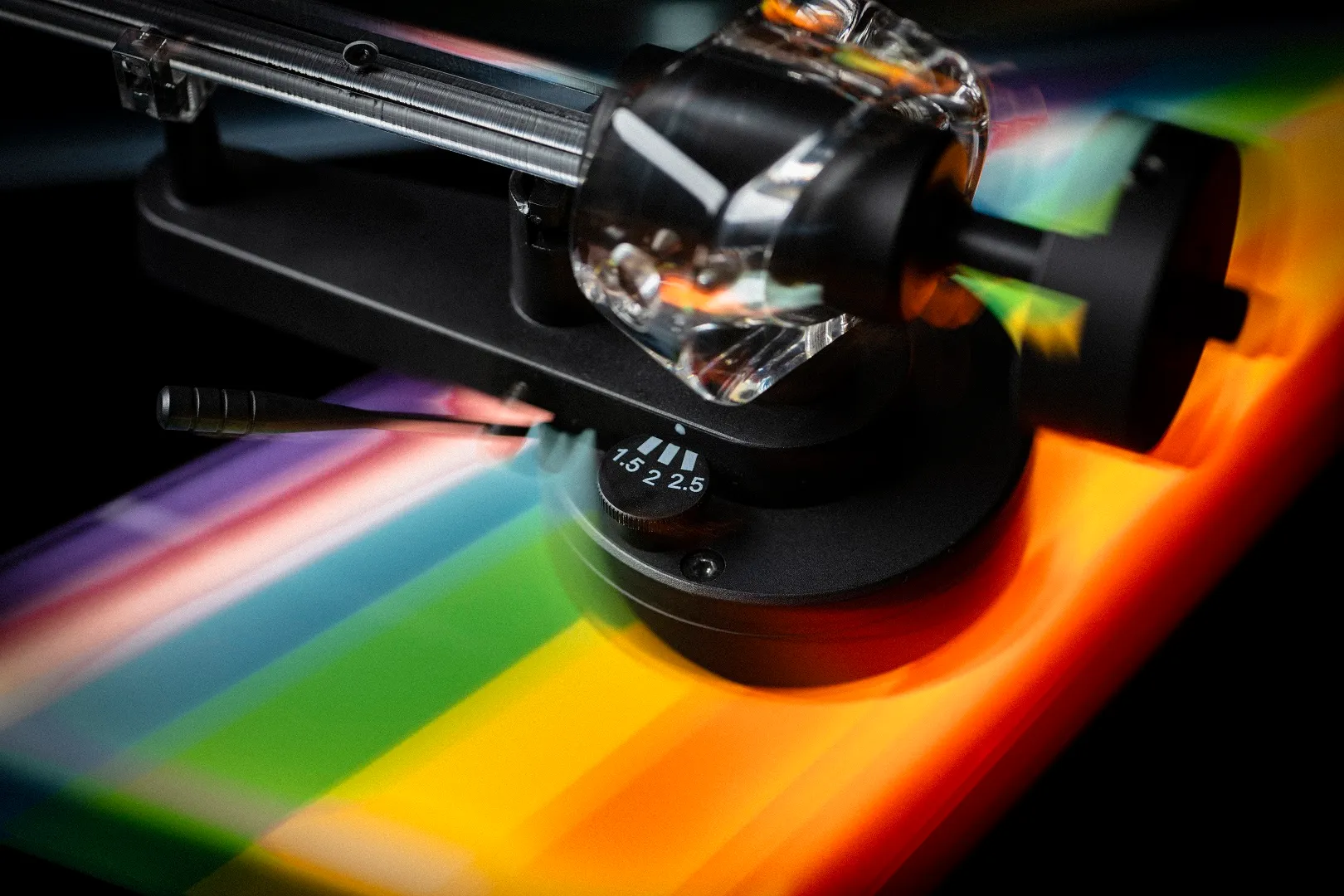 Nahaufnahme eines Plattenspielerarms mit regenbogenfarbenem Hintergrund.