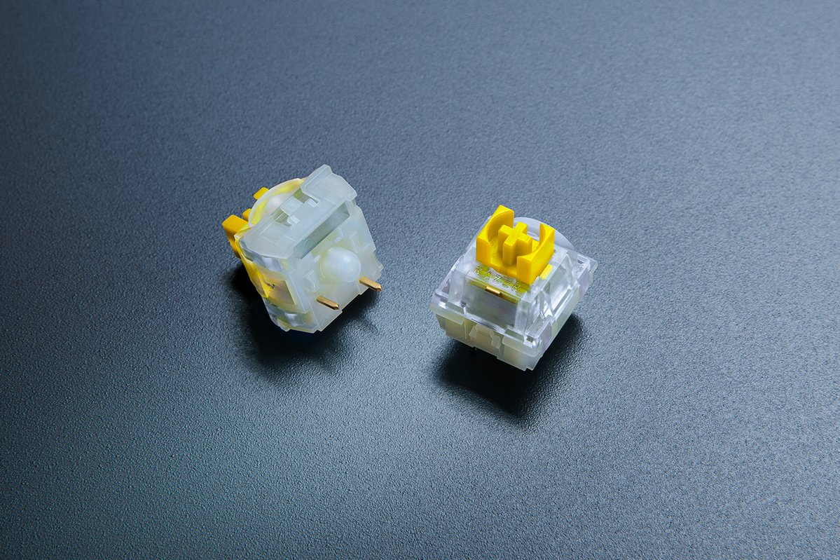 Zwei gelbe und transparente mechanische Tastaturschalter auf dunkler Oberfläche.