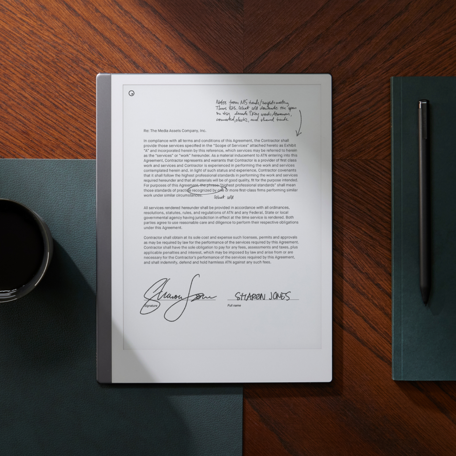 Een hand die met een pen op een digitale notitieblok schrijft, met een kopje koffie.