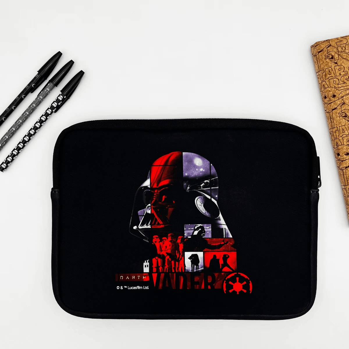 Una funda negra para tableta con un collage de Darth Vader y el logotipo de Star Wars, bolígrafos y un libro.