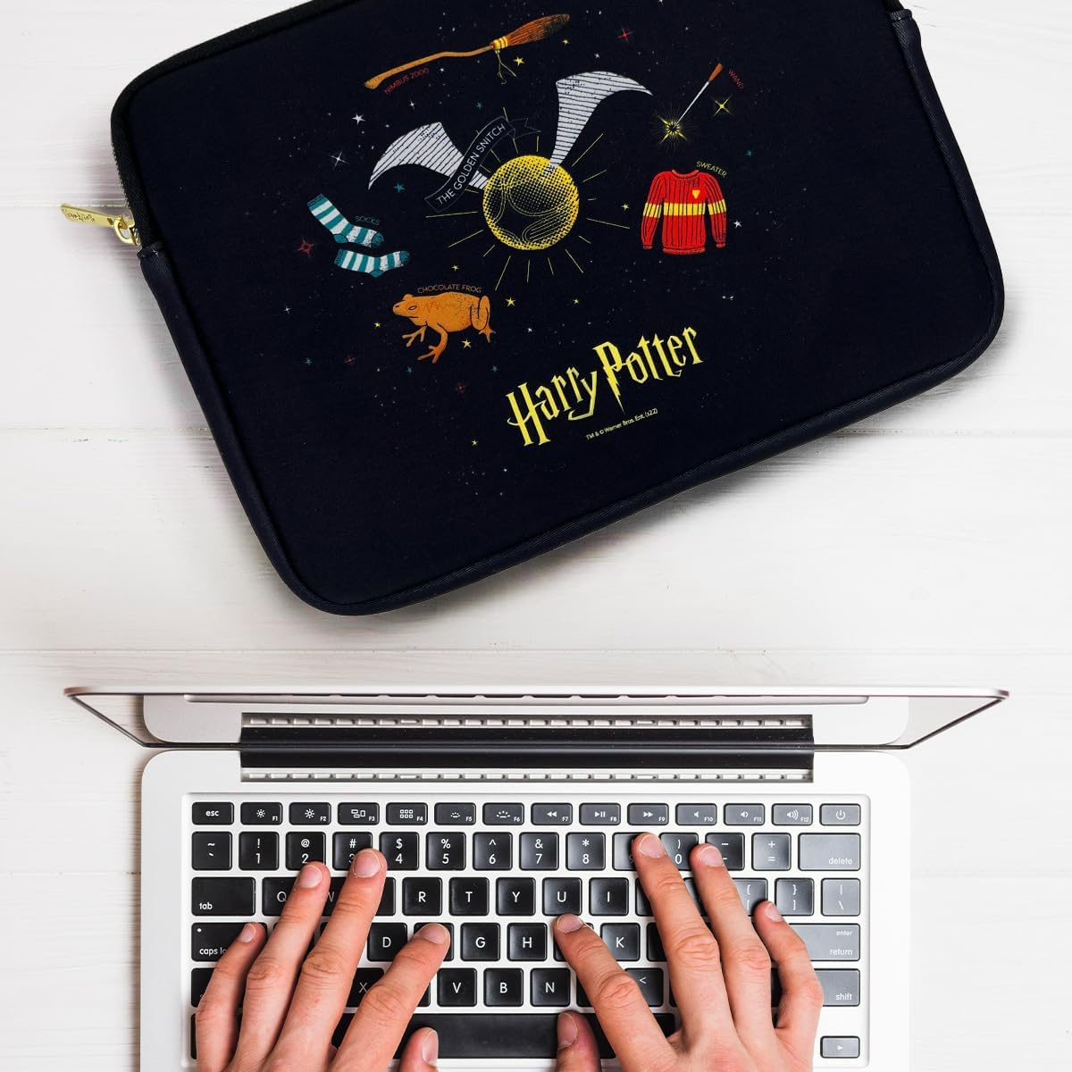 Un portátil en un escritorio con una funda temática de Harry Potter y un teclado.