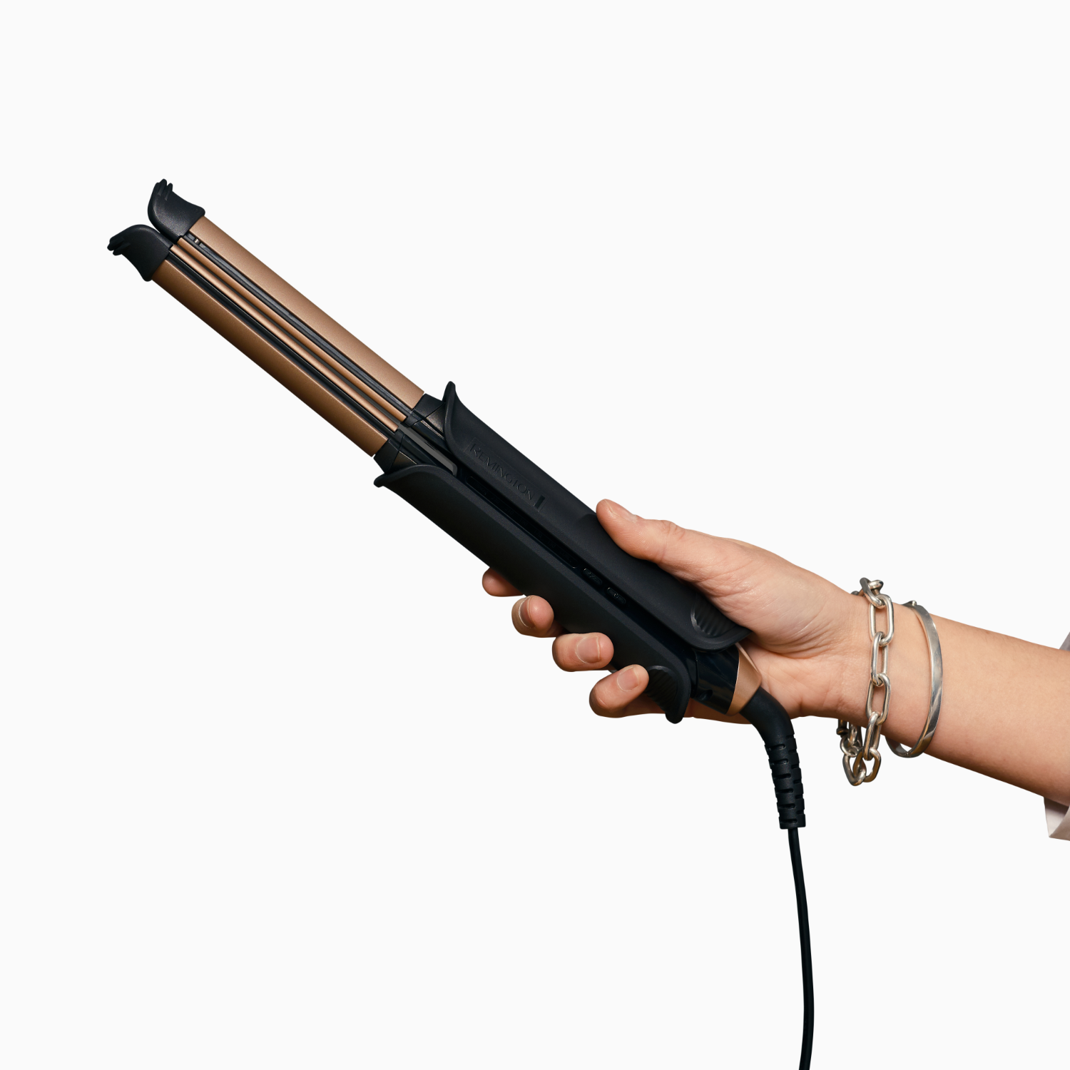 A person's hand holding a black and gold hair crimper.