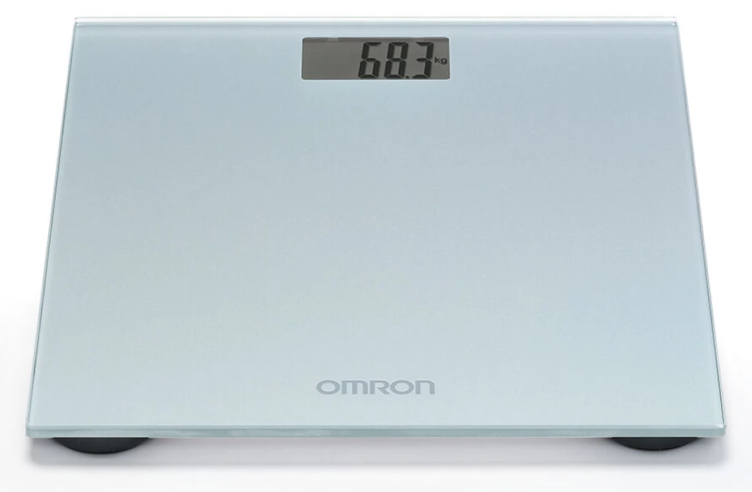 Digitális fürdőszobamérleg, 68,3 kg-ot mutat. A mérleg fehér, üveg felülettel és Omron logóval.