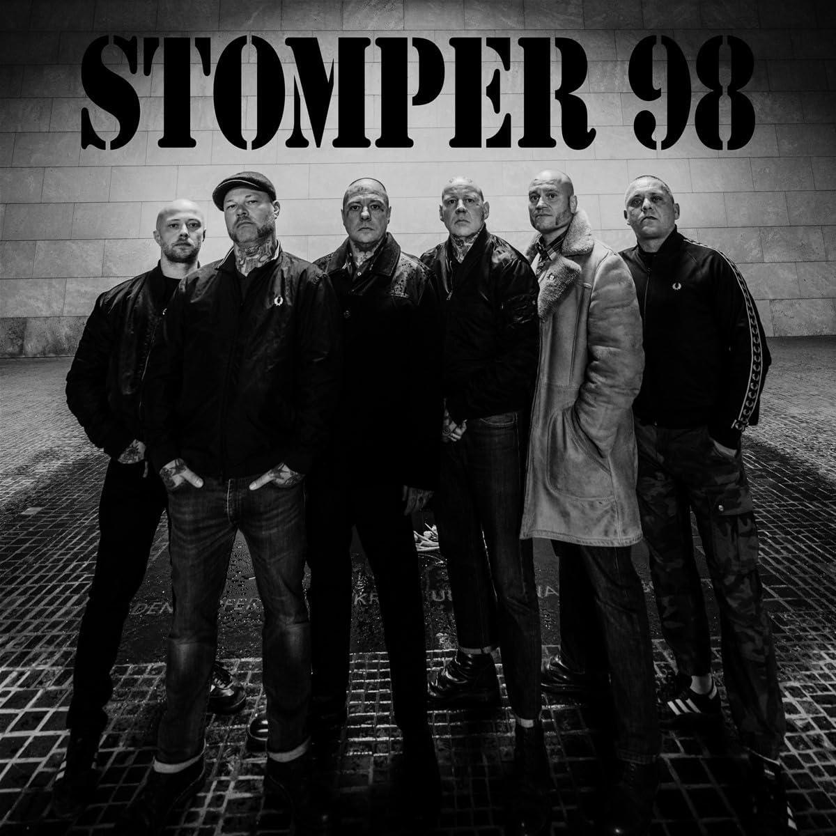 Gruppe von sechs Männern, in dunkler Umgebung, mit dem Text 'STOMPER 98' darüber, in Schwarzweiß.