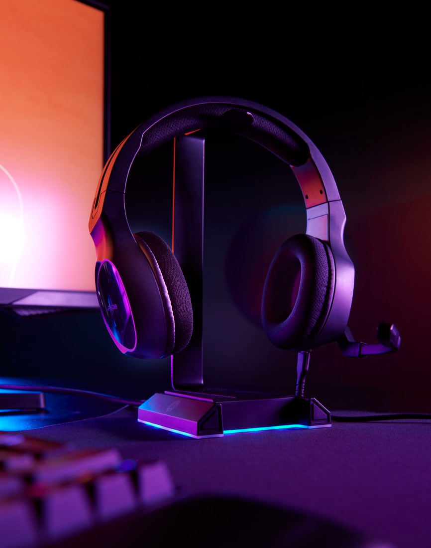 Fekete gamer fejhallgató egy állványon, színes fénnyel az alján.