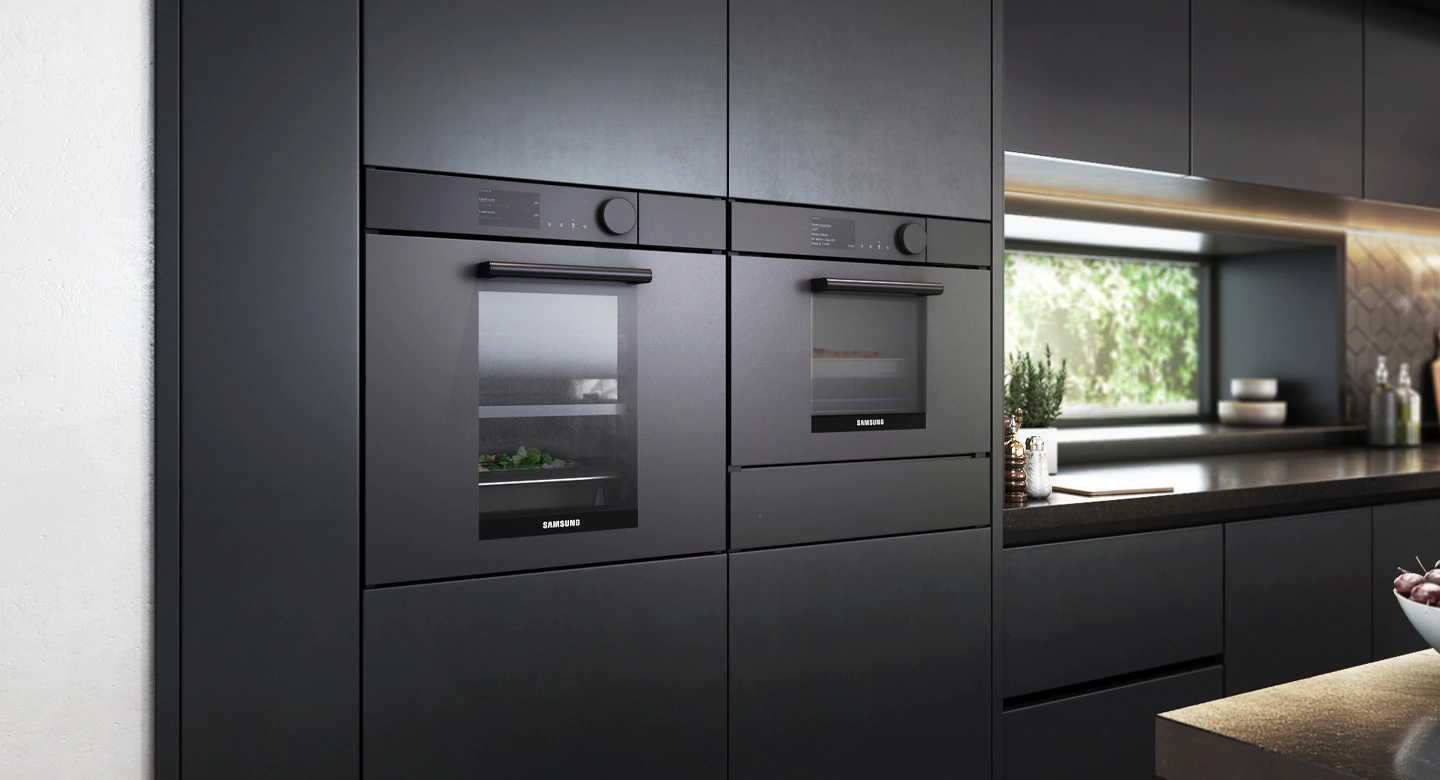 Dwa czarne piekarniki do zabudowy w nowoczesnej kuchni. Piekarniki są eleganckie, z czarnymi drzwiami i panelami sterowania.