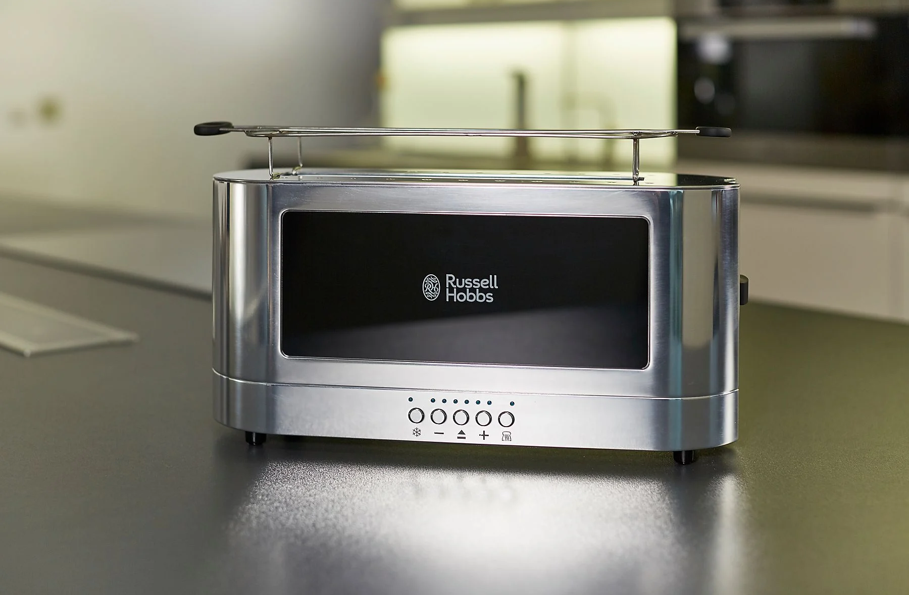 Ezüst Russell Hobbs kenyérpirító az asztalon. Jól megvilágított, modern konyhában van.