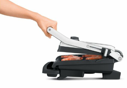 Kéz működtet egy grillt kolbászokkal, fehér háttérrel.
